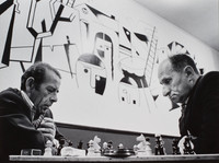 Chess players at the Jewish Club in Lodz.  At the outbreak of WW II, one-third of the city (230,000) were Jewish.  Now (1975) approximately 500 are left. Some gathering here to socialize, watch television, play cards...  The mural, done in 1960, by Adam (Aron)  Muszka, depicts the holocaust.